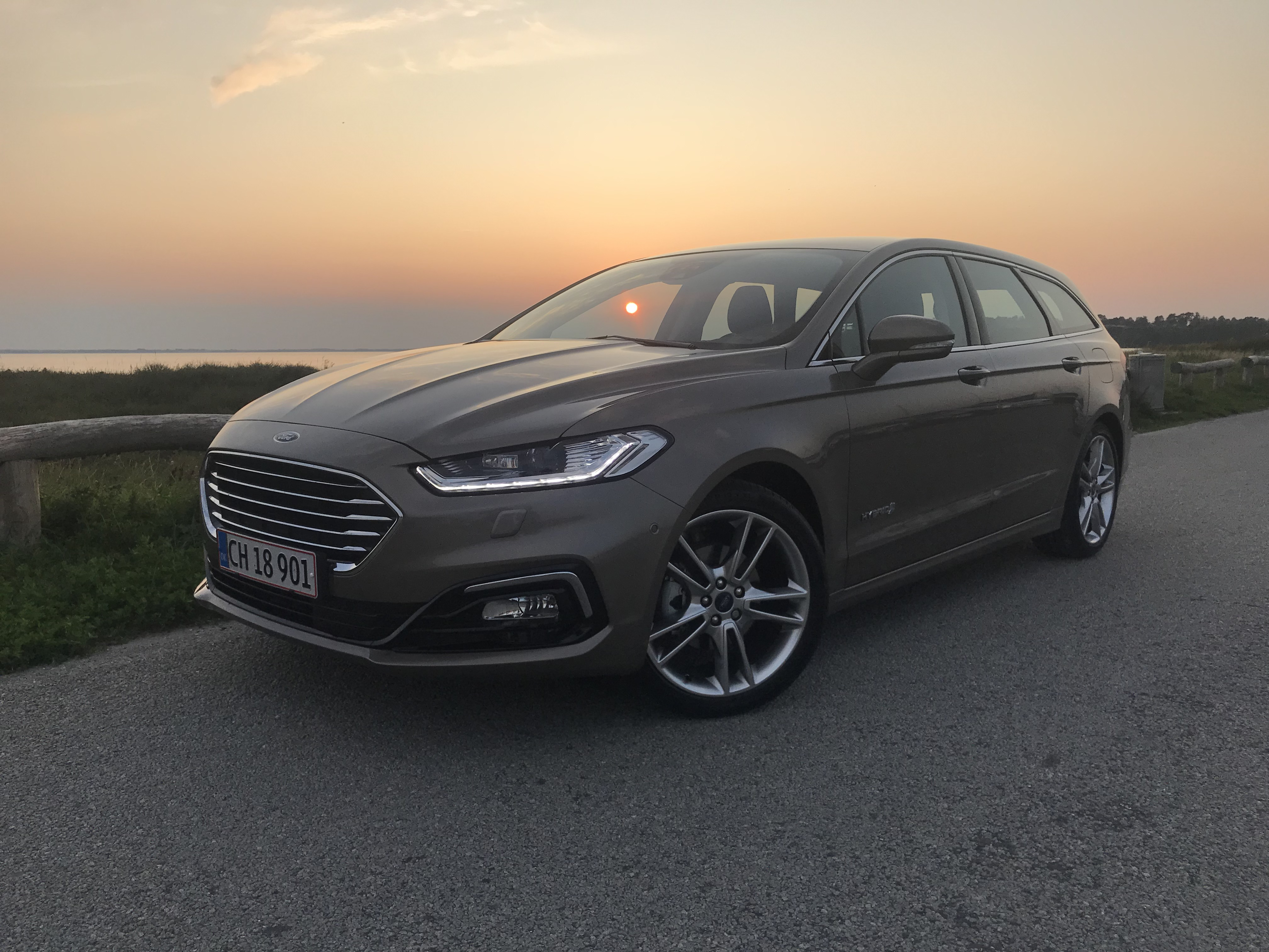Ford Mondeo Hybrid med solnedgang over Isefjorden i baggrunden.